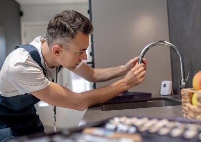 water-tap-prevention-concentrated-man-leaning-water-faucet-touching-spout-pipe_259150-58276